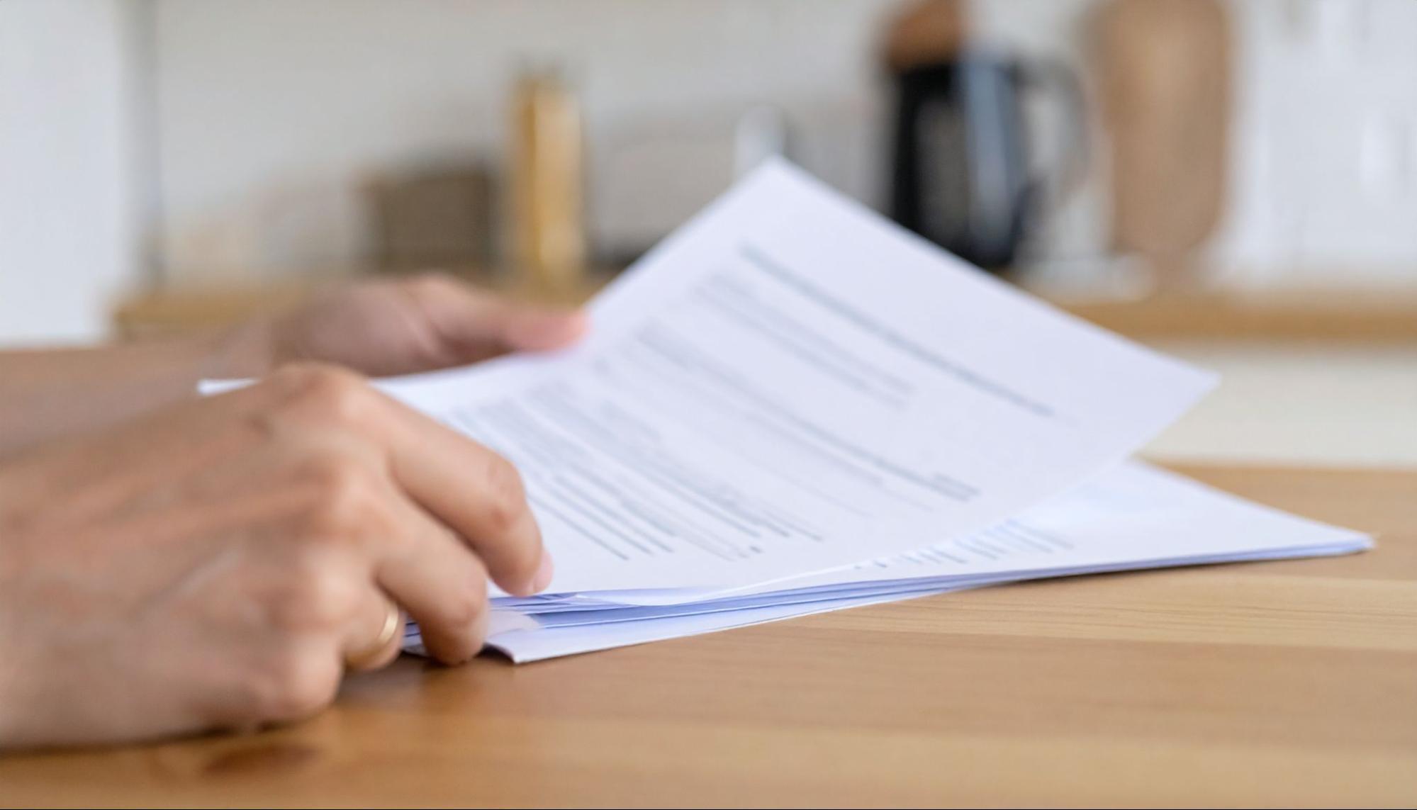 Reviewing a denied homeowners insurance claim — know your next steps Hands holding insurance claim denial letter at kitchen table
